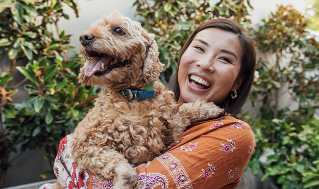 A woman holding a dog and smiling